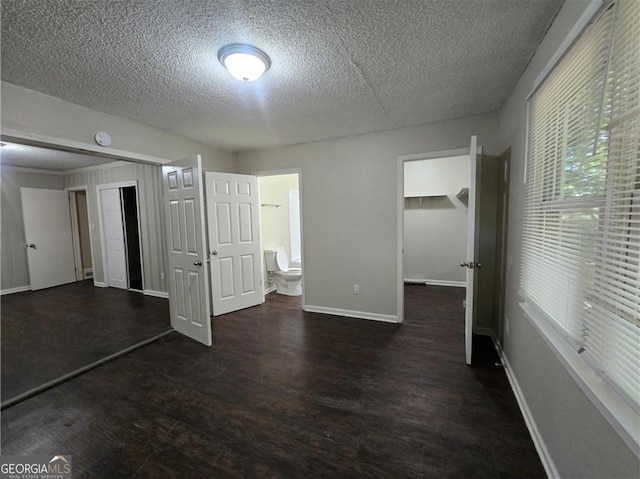 767 Vinson Pl SW, Atlanta, GA 30315 - unfurnished bedroom with a closet, wood finished floors, a textured ceiling, baseboards, and a walk in closet