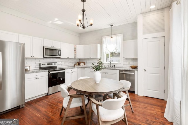 11 Pine St, Covington, GA 30014 - kitchen featuring appliances with stainless steel finishes, a sink, a chandelier, decorative backsplash, and dark wood-style flooring