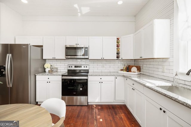 11 Pine St, Covington, GA 30014 - kitchen featuring appliances with stainless steel finishes, dark wood-style floors, white cabinets, a sink, and tasteful backsplash