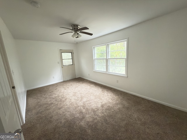 carpeted spare room with a ceiling fan, baseboards, and a smoke detector
