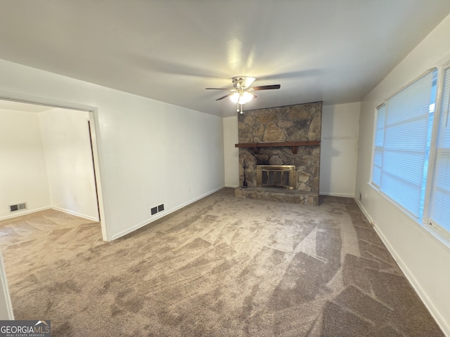 unfurnished living room with carpet floors, ceiling fan, a fireplace, and baseboards