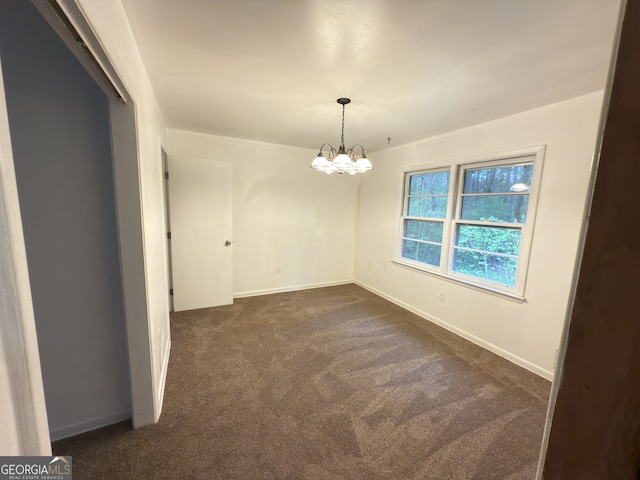 unfurnished dining area with dark colored carpet, a chandelier, and baseboards