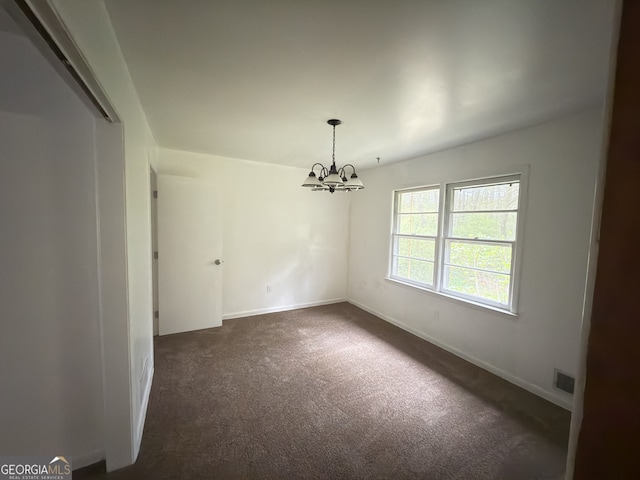 unfurnished room featuring dark carpet, a chandelier, and baseboards