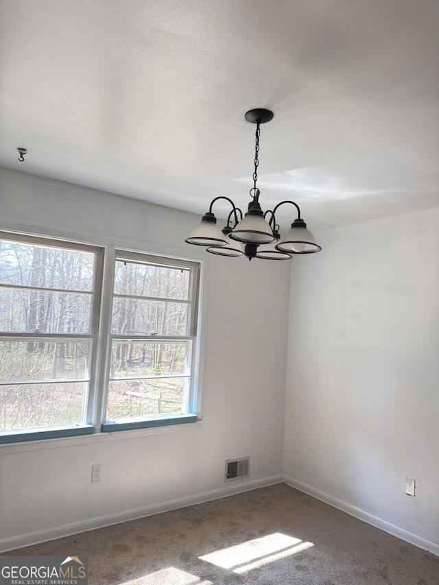 unfurnished dining area featuring a chandelier, carpet floors, and baseboards