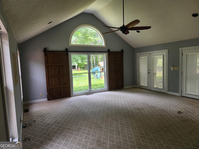 carpeted empty room with a barn door, baseboards, a ceiling fan, high vaulted ceiling, and a textured ceiling