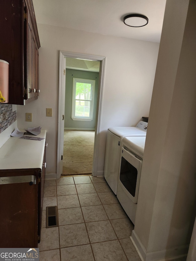 laundry room featuring washing machine and clothes dryer, cabinet space, light tile patterned floors, and baseboards