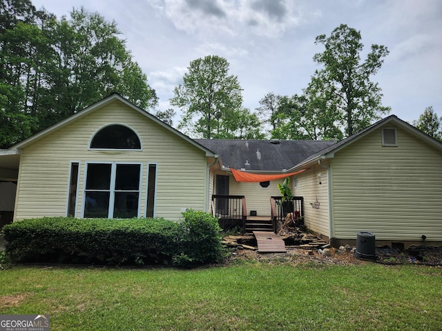 rear view of house featuring a wooden deck and a yard