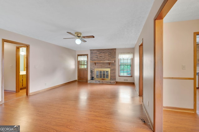 95 Stephens Dr, Covington, GA 30016 - unfurnished living room featuring light wood-style floors, a ceiling fan, a brick fireplace, and baseboards