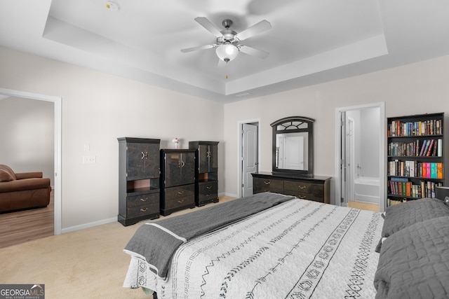 bedroom featuring a tray ceiling, baseboards, and carpet floors