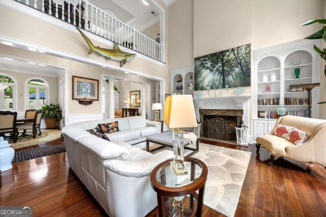 3182 Deepwater Dr, Gainesville, GA 30506 - living room featuring a towering ceiling, a high end fireplace, wood finished floors, built in shelves, and ornamental molding