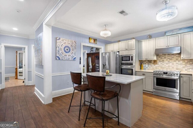 3182 Deepwater Dr, Gainesville, GA 30506 - kitchen featuring appliances with stainless steel finishes, under cabinet range hood, a breakfast bar, a kitchen island, and crown molding