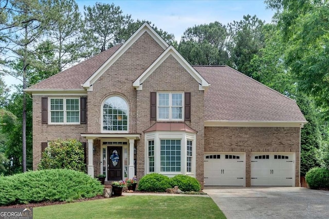 view of front facade featuring brick siding, concrete driveway, roof with shingles, a front yard, and an attached garage