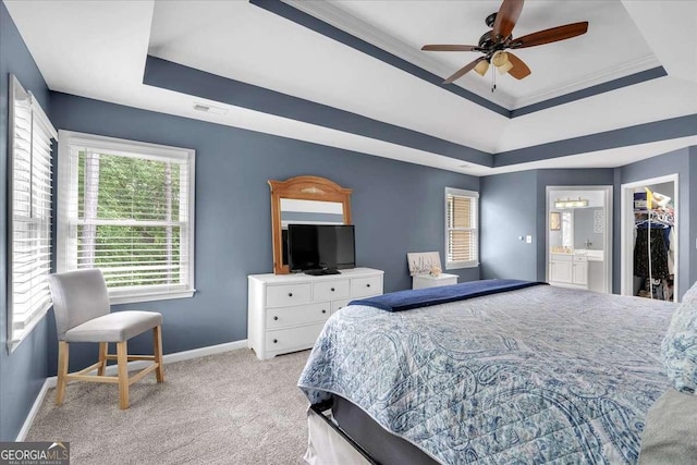 bedroom featuring a raised ceiling, light carpet, baseboards, a spacious closet, and crown molding