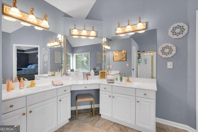 ensuite bathroom featuring a shower stall, vanity, baseboards, and lofted ceiling