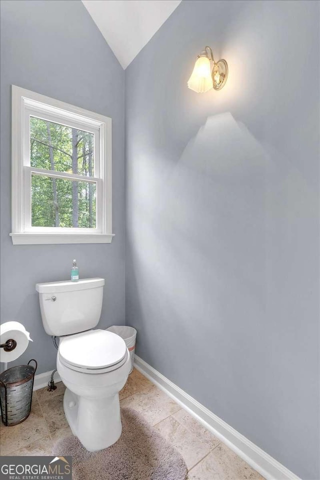 bathroom featuring baseboards, toilet, lofted ceiling, and tile patterned floors