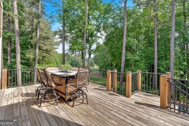 wooden terrace featuring outdoor dining area and view of scattered trees