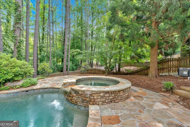 view of pool featuring a fenced backyard and a pool with connected hot tub