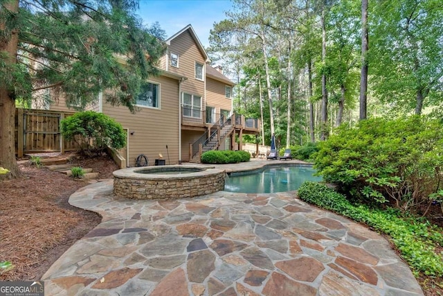 swimming pool featuring stairs, an in-ground hot tub, a deck, fence, and a patio