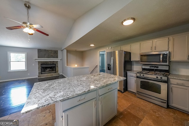 180 Old Airport Rd, Carrollton, GA 30116 - kitchen featuring appliances with stainless steel finishes, vaulted ceiling, ceiling fan, light stone counters, and a stone fireplace