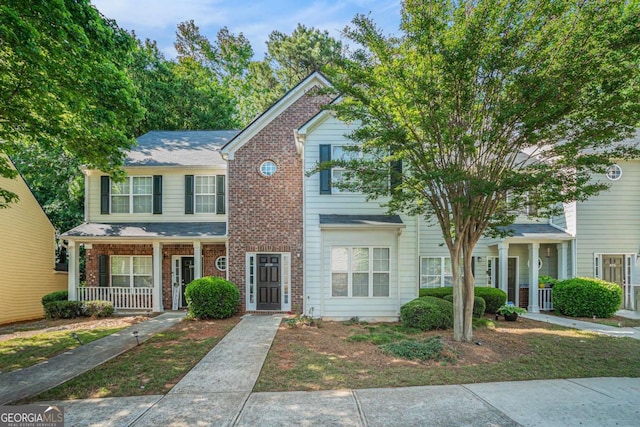 townhome / multi-family property with a porch and brick siding