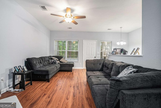 living area featuring a chandelier, wood finished floors, a ceiling fan, and baseboards