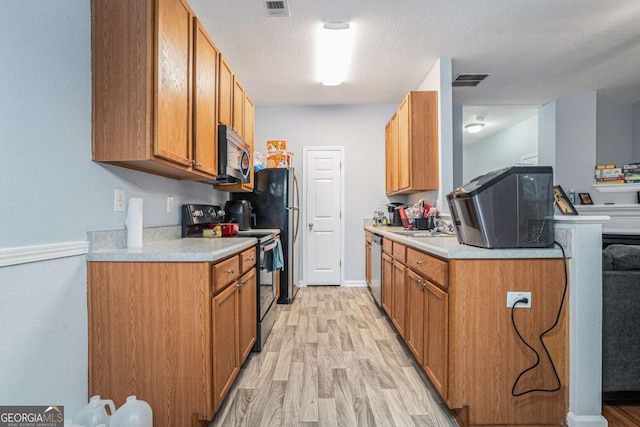 kitchen with appliances with stainless steel finishes, light wood finished floors, light countertops, brown cabinets, and baseboards