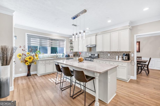 1500 Highland Farm Dr, Suwanee, GA 30024 - kitchen featuring gas stove, under cabinet range hood, a breakfast bar area, crown molding, and a sink