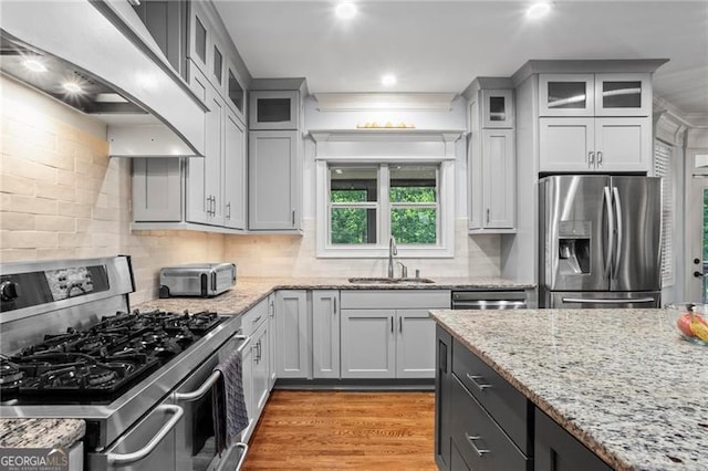 7493 Elderberry Dr, Douglasville, GA 30135 - kitchen featuring appliances with stainless steel finishes, a sink, wall chimney range hood, tasteful backsplash, and light wood-type flooring