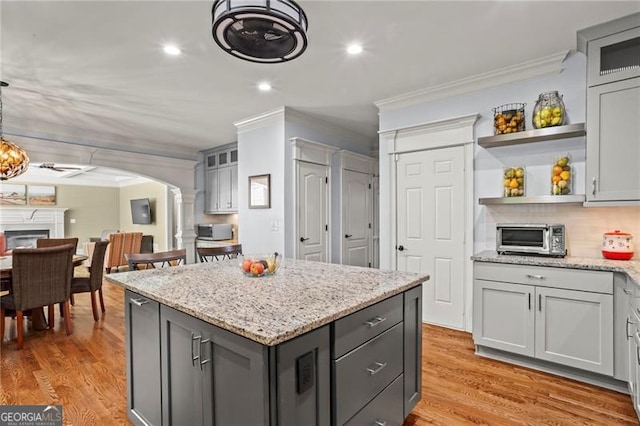 7493 Elderberry Dr, Douglasville, GA 30135 - kitchen featuring crown molding, ornate columns, arched walkways, gray cabinetry, and open shelves
