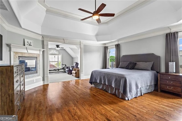 7493 Elderberry Dr, Douglasville, GA 30135 - bedroom featuring ornamental molding, a tray ceiling, wood finished floors, ceiling fan, and a tiled fireplace