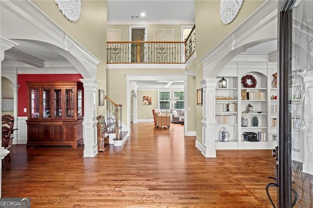 7493 Elderberry Dr, Douglasville, GA 30135 - foyer featuring wood finished floors, arched walkways, stairway, crown molding, and a towering ceiling