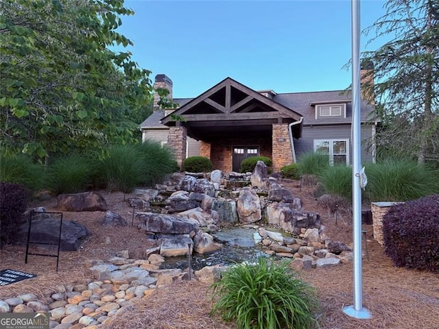 1399 Kilchis Falls Way, Braselton, GA 30517 - view of front facade featuring a chimney, a small pond, and stone siding
