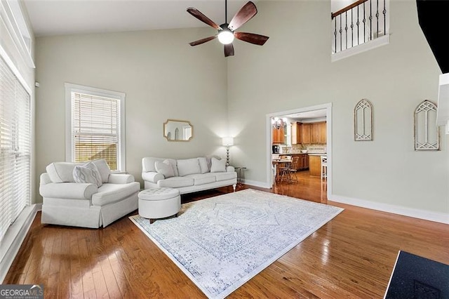 1399 Kilchis Falls Way, Braselton, GA 30517 - living room with high vaulted ceiling, a ceiling fan, wood-type flooring, and baseboards