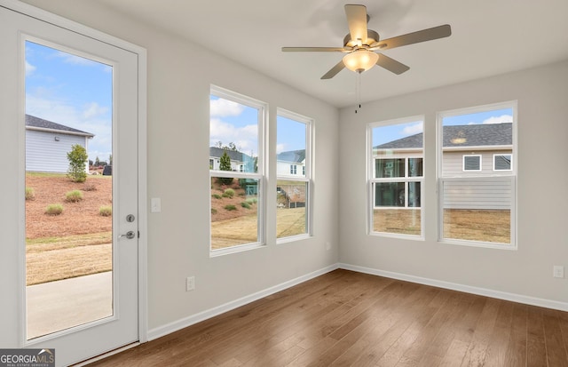 doorway with baseboards, hardwood / wood-style floors, and a ceiling fan