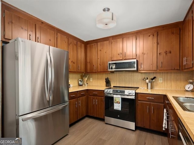 2458 Zachary Woods Dr, Marietta, GA 30064 - kitchen featuring appliances with stainless steel finishes, light countertops, tasteful backsplash, light wood-style flooring, and a sink