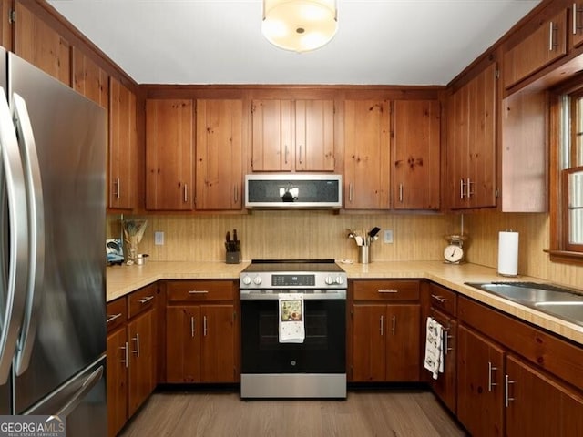 2458 Zachary Woods Dr, Marietta, GA 30064 - kitchen featuring stainless steel appliances, light countertops, light wood finished floors, and tasteful backsplash