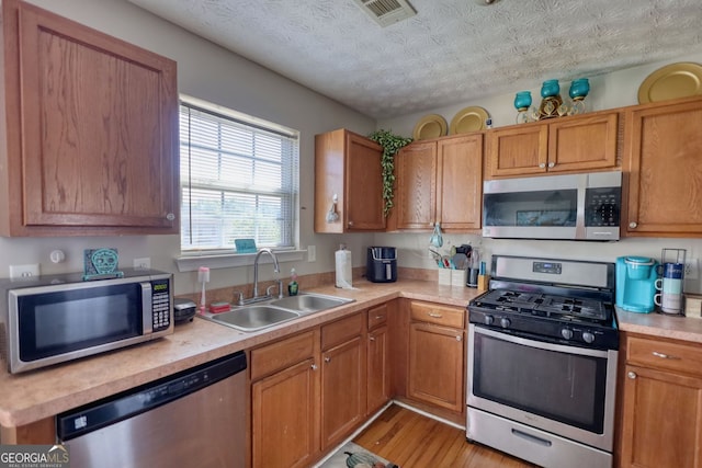 2000 Redwood Trce, Ellenwood, GA 30294 - kitchen with stainless steel appliances, light countertops, light wood-style flooring, and brown cabinetry