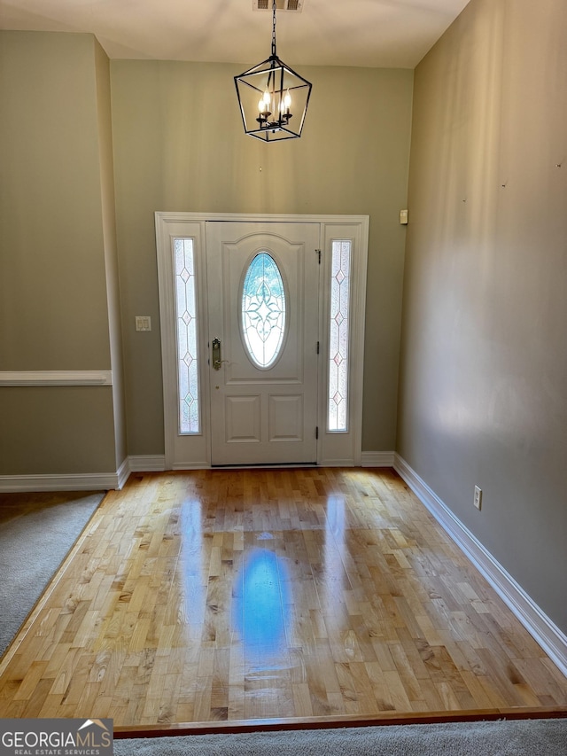 entryway featuring baseboards, wood finished floors, and a chandelier