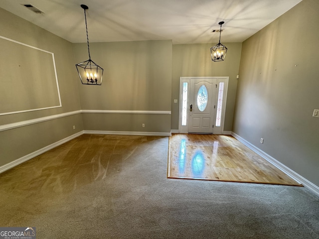 foyer with a chandelier, carpet, and baseboards
