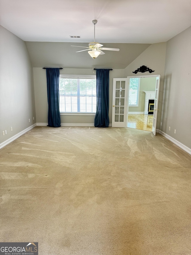 unfurnished living room with lofted ceiling, baseboards, a ceiling fan, plenty of natural light, and carpet floors