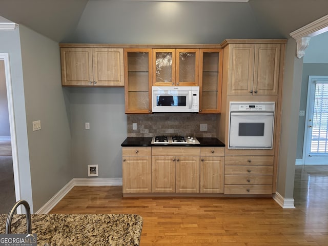 kitchen with white appliances, vaulted ceiling, dark countertops, tasteful backsplash, and light wood-style flooring