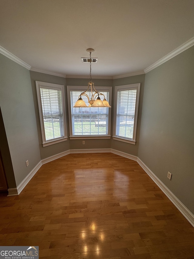 unfurnished dining area with healthy amount of natural light, baseboards, wood finished floors, and ornamental molding