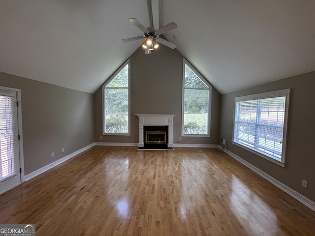 unfurnished living room with a fireplace with raised hearth, a ceiling fan, wood finished floors, lofted ceiling, and baseboards