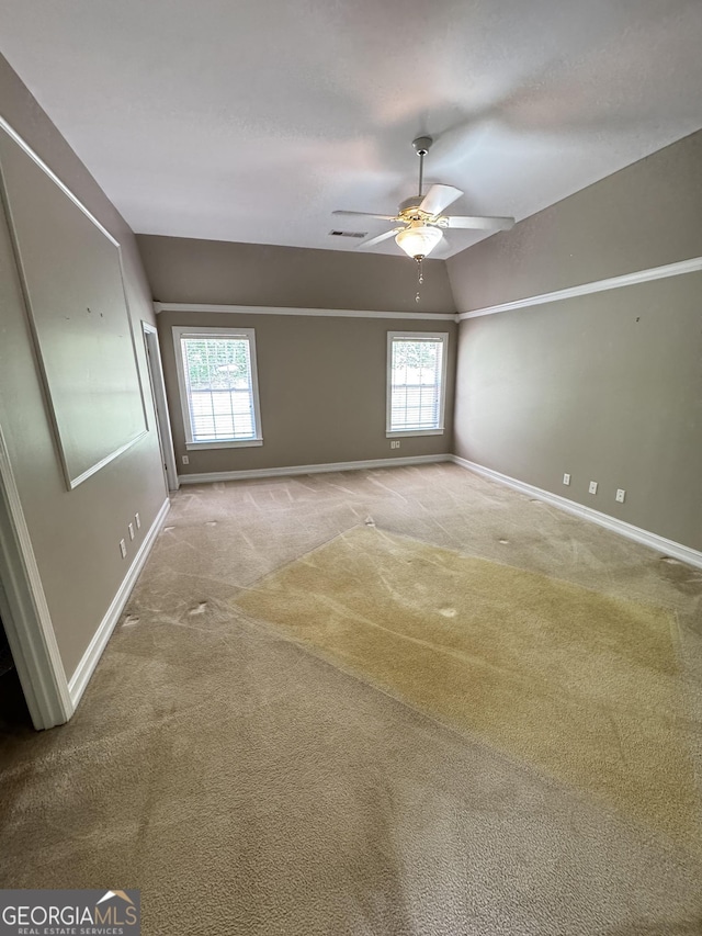 unfurnished room with carpet flooring, baseboards, vaulted ceiling, and a ceiling fan
