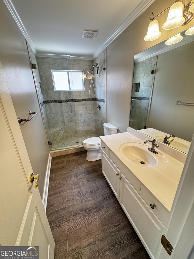 bathroom with toilet, a stall shower, ornamental molding, vanity, and wood finished floors