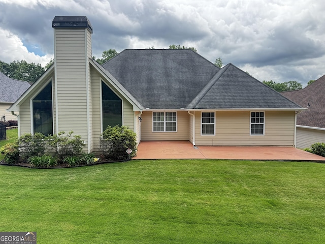 back of house with a lawn, a patio, a chimney, and roof with shingles
