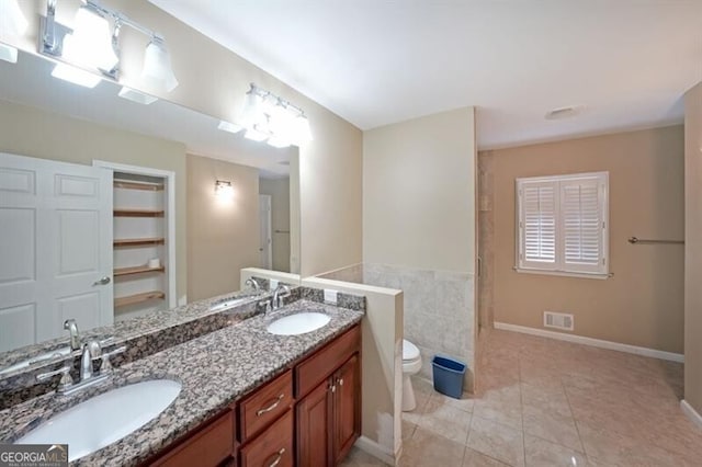 bathroom with tile patterned flooring, toilet, double vanity, and baseboards