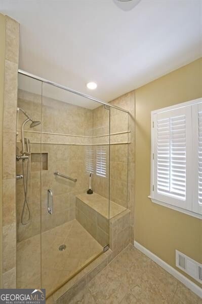 full bath with a stall shower, baseboards, and tile patterned floors