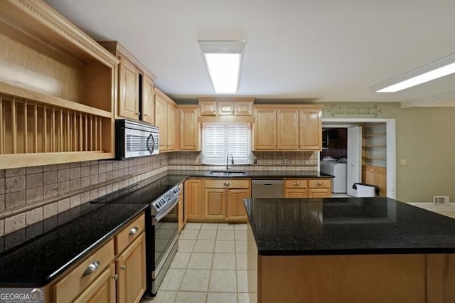 kitchen with appliances with stainless steel finishes, separate washer and dryer, decorative backsplash, a sink, and light tile patterned floors