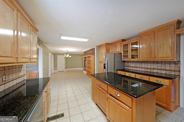 kitchen featuring appliances with stainless steel finishes, a chandelier, tasteful backsplash, glass insert cabinets, and baseboards